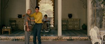 Movie still from “The Best Exotic Marigold Hotel” (2011), directed by John Madden – A young man standing in front of two other men; Wide shot, Over the shoulder angle
