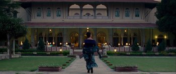Movie still from “The Best Exotic Marigold Hotel” (2011), directed by John Madden – A woman walking down a path in front of a building; Extreme Wide shot, Low angle