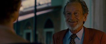 Movie still from “The Best Exotic Marigold Hotel” (2011), directed by John Madden – An older man wearing a suit and tie smiling; Close Up shot, Low angle