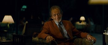 Movie still from “The Best Exotic Marigold Hotel” (2011), directed by John Madden – An older man sitting in a chair wearing a suit and tie; Medium shot, Low angle