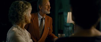 Movie still from “The Best Exotic Marigold Hotel” (2011), directed by John Madden – An older man wearing a suit and a tie sitting at a table; Medium shot, Over the shoulder angle