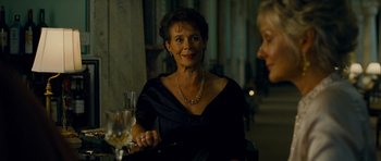 Movie still from “The Best Exotic Marigold Hotel” (2011), directed by John Madden – An older woman sitting at a table with a glass of wine; Close Up shot, Over the shoulder angle