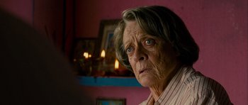 Movie still from “The Best Exotic Marigold Hotel” (2011), directed by John Madden – An older woman looking at the camera in a pink room; Close Up shot, Over the shoulder angle