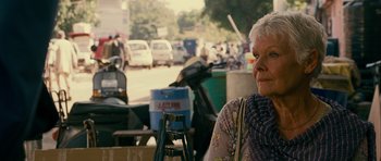 Movie still from “The Best Exotic Marigold Hotel” (2011), directed by John Madden – An older woman sitting in a parking lot next to parked motorcycles; Close Up shot, Over the shoulder angle