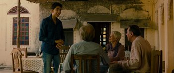 Movie still from “The Best Exotic Marigold Hotel” (2011), directed by John Madden – A group of people sitting around a table talking to each other; Medium shot, Over the shoulder angle