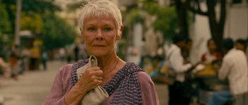 Movie still from “The Best Exotic Marigold Hotel” (2011), directed by John Madden – An older woman holding a purse while standing on a sidewalk; Close Up shot, Low angle