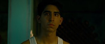 Movie still from “The Best Exotic Marigold Hotel” (2011), directed by John Madden – A young man looking into the distance in a dark room; Close Up shot, Low angle