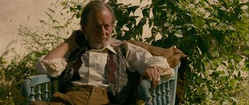 Movie still from “The Best Exotic Marigold Hotel” (2011), directed by John Madden – An older man sitting on a chair in a yard; Medium shot, Low angle