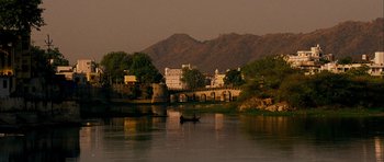 Movie still from “The Best Exotic Marigold Hotel” (2011), directed by John Madden – A small boat on a river near a bridge and mountains; Extreme Wide shot, High angle