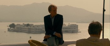 Movie still from “The Best Exotic Marigold Hotel” (2011), directed by John Madden – A man in a suit sitting on top of a boat; Medium shot, Low angle
