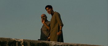 Movie still from “The Best Exotic Marigold Hotel” (2011), directed by John Madden – Two men standing on a ledge in front of a sky background; Medium shot, Low angle
