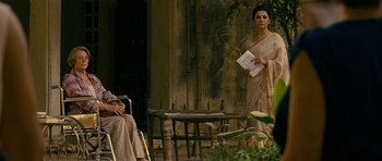 Movie still from “The Best Exotic Marigold Hotel” (2011), directed by John Madden – A woman standing next to a table holding papers in her hands; Medium shot, Over the shoulder angle