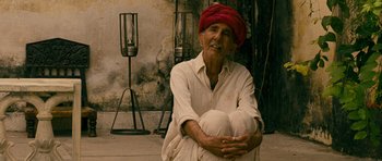 Movie still from “The Best Exotic Marigold Hotel” (2011), directed by John Madden – An old man sitting on the ground wearing a red turban; Medium shot, High angle