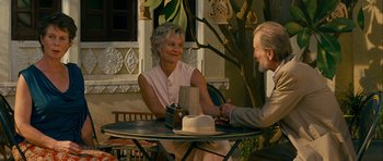 Movie still from “The Best Exotic Marigold Hotel” (2011), directed by John Madden – An older woman sitting at a table with a man; Medium shot, Over the shoulder angle