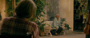 Movie still from “The Best Exotic Marigold Hotel” (2011), directed by John Madden – An older woman sitting on top of a white bench; Wide shot, Over the shoulder angle