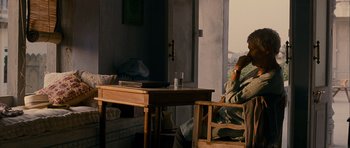 Movie still from “The Best Exotic Marigold Hotel” (2011), directed by John Madden – A man sitting at a table in front of an open door; Medium shot, High angle