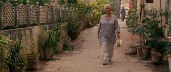 Movie still from “The Best Exotic Marigold Hotel” (2011), directed by John Madden – An older woman walking down a sidewalk with a hat on; Wide shot, Low angle