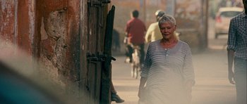Movie still from “The Best Exotic Marigold Hotel” (2011), directed by John Madden – An older woman walking down the street with a bicycle; Medium shot, Over the shoulder angle