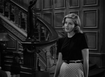 Movie still from “The Big Sleep” (1946), directed by Howard Hawks – A black and white photo of a woman standing in front of a staircase; Medium shot, Low angle