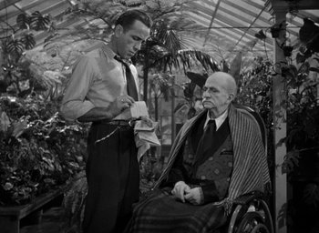 Movie still from “The Big Sleep” (1946), directed by Howard Hawks – An older man sitting in a wheelchair next to a younger man; Medium shot, Low angle