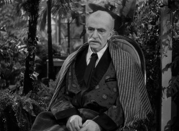 Movie still from “The Big Sleep” (1946), directed by Howard Hawks – An older man sitting in a chair wearing a suit and tie; Medium shot, High angle