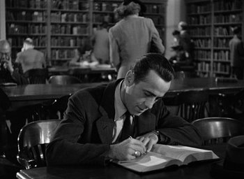 Movie still from “The Big Sleep” (1946), directed by Howard Hawks – A black and white photo of a man writing in a book; Medium shot, High angle