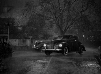 Movie still from “The Big Sleep” (1946), directed by Howard Hawks – A black and white photo of a car in the rain; Extreme Wide shot, High angle