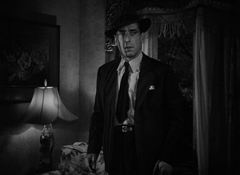 Movie still from “The Big Sleep” (1946), directed by Howard Hawks – A black and white photo of a man in a suit and hat; Medium shot, Low angle
