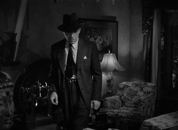 Movie still from “The Big Sleep” (1946), directed by Howard Hawks – A black and white photo of a man in a suit and hat; Medium shot, Low angle