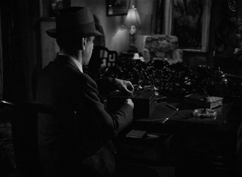 Movie still from “The Big Sleep” (1946), directed by Howard Hawks – A black and white photo of a man sitting at a table; Medium shot, High angle