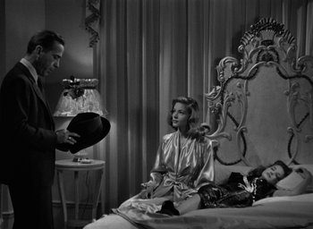 Movie still from “The Big Sleep” (1946), directed by Howard Hawks – A man and a woman sitting on top of a bed in a room; Medium shot, High angle