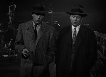 Movie still from “The Big Sleep” (1946), directed by Howard Hawks – A couple of men standing next to each other wearing hats; Medium shot, Low angle