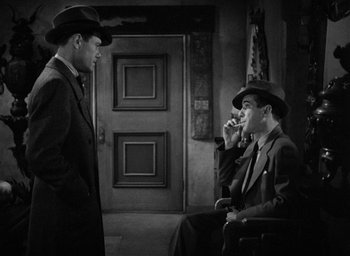 Movie still from “The Big Sleep” (1946), directed by Howard Hawks – Two men in suits and hats are talking to each other; Medium shot, High angle