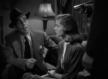 Movie still from “The Big Sleep” (1946), directed by Howard Hawks – A black and white photo of a man and a woman sitting on a couch; Medium shot, Over the shoulder angle