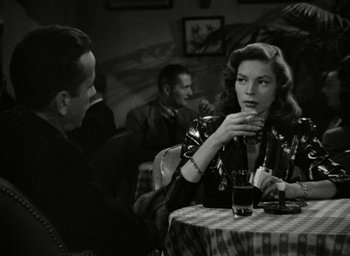 Movie still from “The Big Sleep” (1946), directed by Howard Hawks – A man and a woman sitting at a table with a drink; Medium shot, Over the shoulder angle