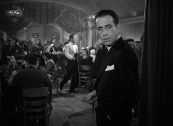 Movie still from “The Big Sleep” (1946), directed by Howard Hawks – A black and white photo of a man in a restaurant; Medium shot, Over the shoulder angle
