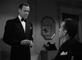 Movie still from “The Big Sleep” (1946), directed by Howard Hawks – A man in a suit talking to another man in a suit; Medium shot, Over the shoulder angle