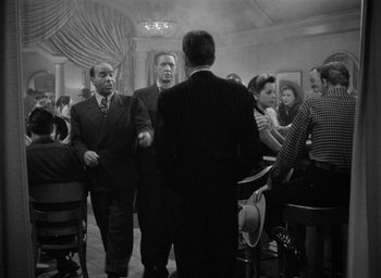 Movie still from “The Big Sleep” (1946), directed by Howard Hawks – A black and white photo of a group of men and women; Wide shot, Low angle
