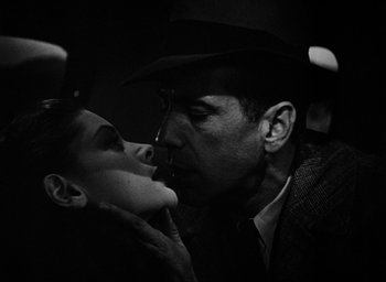 Movie still from “The Big Sleep” (1946), directed by Howard Hawks – A black and white photo of a man and a woman kissing; Close Up shot, Low angle