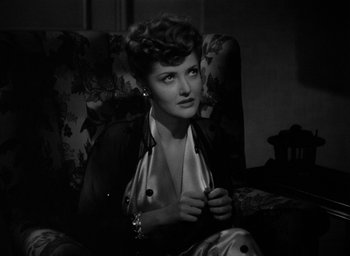 Movie still from “The Big Sleep” (1946), directed by Howard Hawks – A black and white photo of a woman sitting on a couch; Close Up shot, High angle