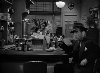 Movie still from “The Big Sleep” (1946), directed by Howard Hawks – A man sitting at a counter in a restaurant; Medium shot, Over the shoulder angle
