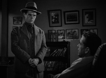 Movie still from “The Big Sleep” (1946), directed by Howard Hawks – A man wearing a hat and a suit standing in front of a man; Medium shot, Over the shoulder angle