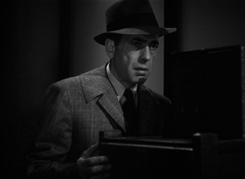 Movie still from “The Big Sleep” (1946), directed by Howard Hawks – A black and white photo of a man in a suit and hat; Close Up shot, Low angle