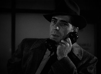 Movie still from “The Big Sleep” (1946), directed by Howard Hawks – A man wearing a hat and holding a cell phone to his ear; Close Up shot, High angle