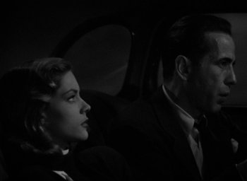 Movie still from “The Big Sleep” (1946), directed by Howard Hawks – A man and a woman sitting in the back of a car; Close Up shot, Low angle