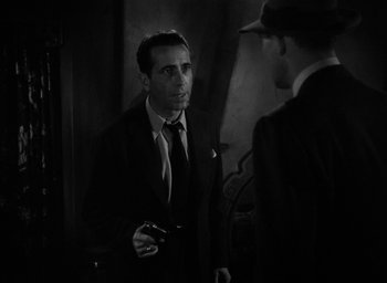 Movie still from “The Big Sleep” (1946), directed by Howard Hawks – A man in a suit and tie talking to another man; Close Up shot, Over the shoulder angle