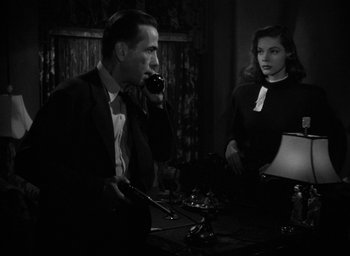 Movie still from “The Big Sleep” (1946), directed by Howard Hawks – A man and a woman sitting at a table; Medium shot, Low angle