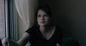 Movie still from “The Blackcoat's Daughter” (2015), directed by Oz Perkins – A woman sitting in front of a window looking at the camera; Close Up shot, Over the shoulder angle