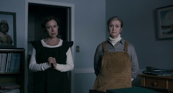 Movie still from “The Blackcoat's Daughter” (2015), directed by Oz Perkins – Two women standing next to each other in front of a door; Medium shot, Low angle