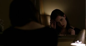 Movie still from “The Blackcoat's Daughter” (2015), directed by Oz Perkins – A woman looking in the mirror in a dark room; Close Up shot, Over the shoulder angle